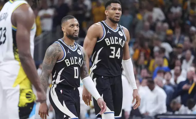 Milwaukee Bucks guard Damian Lillard (0) and forward Giannis Antetokounmpo (34) walk to the bench during the second half of a first-round NBA basketball playoff game against the Indiana Pacers in Indianapolis, Tuesday, April 22, 2025. (AP Photo/Michael Conroy)