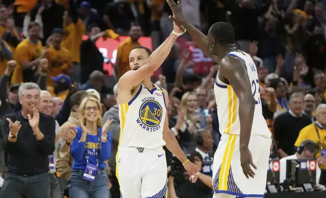 Golden State Warriors guard Stephen Curry (30) is congratulated by forward Draymond Green after making a 3-point basket during the second half of an NBA play-in tournament basketball game against the Memphis Grizzlies in San Francisco, Tuesday, April 15, 2025. (AP Photo/Jeff Chiu)