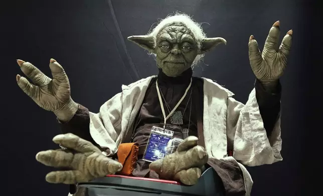 A Star Wars fan dressed as Yoda tries to look airborne during a fan convention called the Star Wars Celebration Japan in Chiba, near Tokyo, Friday, April 18, 2025. (AP Photo/Hiro Komae)