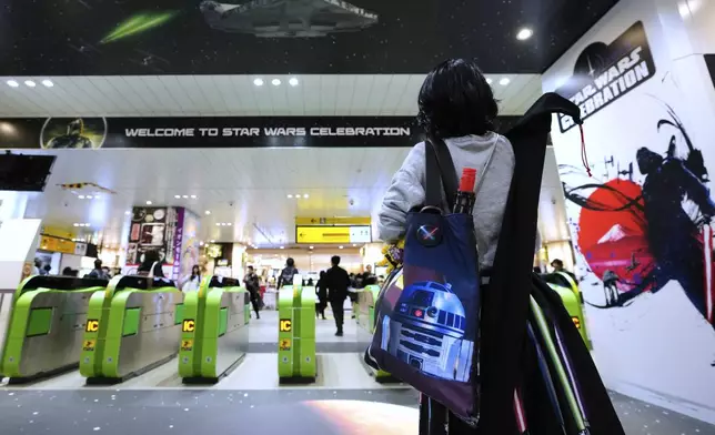 A Star Wars fan takes a photo of event decorations for the Star Wars Celebration at the exit of a train station near the Makuhari Messe convention center in Chiba, near Tokyo, Friday, April 18, 2025. (AP Photo/Hiro Komae)