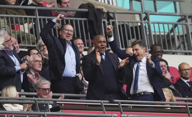 Crystal Palace directors John Textor, left, Mark Bright, centre and Steve Parish celebrate as former Crystal Palace manager Roy Hodgson and his wife Sheila, bottom left, applaud at the end of the English FA Cup semifinal soccer match between Crystal Palace and Aston Villa at the Wembley stadium in London, Saturday, April 26, 2025. (AP Photo/Dave Shopland)