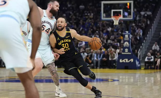 Golden State Warriors guard Stephen Curry (30) moves the ball while defended by San Antonio Spurs forward Sandro Mamukelashvili (54) during the first half of an NBA basketball game Wednesday, April 9, 2025, in San Francisco. (AP Photo/Godofredo A. Vásquez)