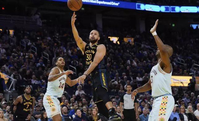 Golden State Warriors guard Stephen Curry (30) shoots next to San Antonio Spurs guard Devin Vassell (24) during the first half of an NBA basketball game Wednesday, April 9, 2025, in San Francisco. (AP Photo/Godofredo A. Vásquez)