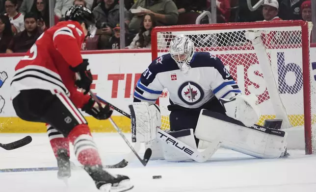 Winnipeg Jets goaltender Connor Hellebuyck (37) stops a shot from Chicago Blackhawks right wing Ilya Mikheyev (95) during the second period of an NHL hockey game Saturday, April 12, 2025, in Chicago. (AP Photo/Erin Hooley)