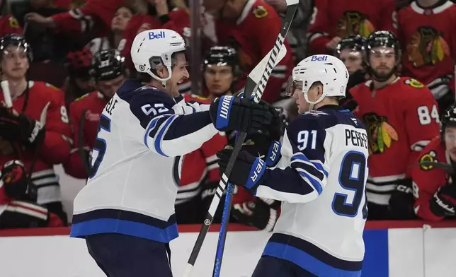 Winnipeg Jets center Mark Scheifele, left, and center Cole Perfetti (91) celebrate after Perfetti's winning shootout goal against the Chicago Blackhawks in an NHL hockey game Saturday, April 12, 2025, in Chicago. (AP Photo/Erin Hooley)