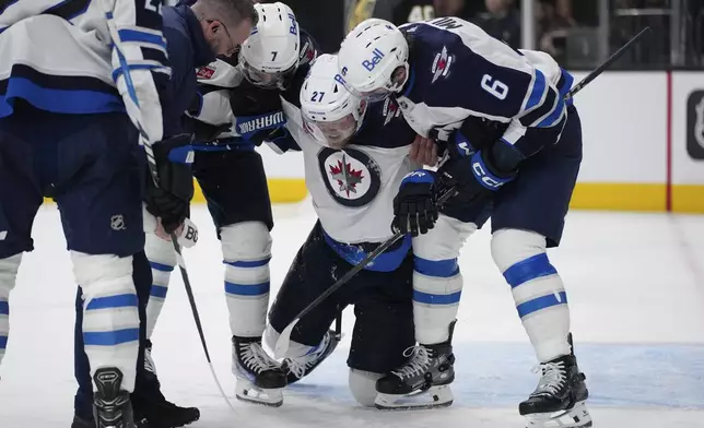 Winnipeg Jets left wing Nikolaj Ehlers (27) is helped off the ice by teammates during the third period of an NHL hockey game against the Vegas Golden Knights, Thursday, April 3, 2025, in Las Vegas. (AP Photo/John Locher)