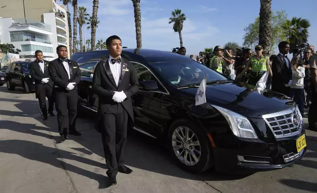 Funeral workers stand beside a hearse driving the coffin of Peruvian Nobel literature laureate Mario Vargas Llosa to a crematorium in Lima, Peru, Monday, April 14, 2025. (AP Photo/Martin Mejia)
