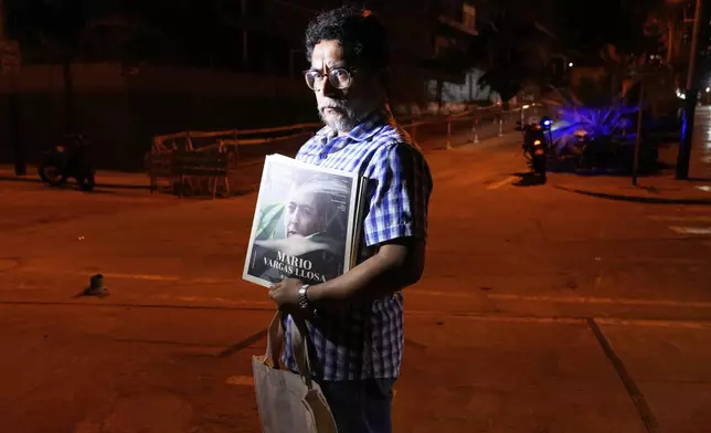 Gabriel Rimachi holds an issue of the literary magazine he directs, dedicated to Peruvian Nobel literature laureate Mario Vargas Llosa, after the announcement of the writer's death at the age of 89, in front of his home in Lima, Peru, Sunday, April 13, 2025. (AP Photo/Martin Mejia)