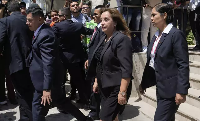 Peruvian President Dina Boluarte, center, is surrounded by security as she leaves the home of the late Peruvian Nobel literature laureate Mario Vargas Llosa, where she gave her condolences to his family the day after his death, in Lima, Peru, Monday, April 14, 2025. (AP Photo/Martin Mejia)