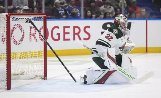Minnesota Wild goalie Filip Gustavsson watches the play as a stick is caught in the net behind him during the first period of an NHL hockey game against the Vancouver Canucks in Vancouver, British Columbia, Saturday, April 12, 2025. (Darryl Dyck/The Canadian Press via AP)