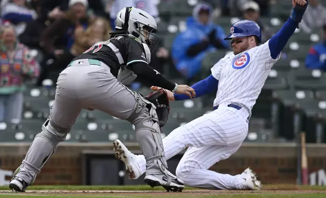 Chicago Cubs' Ian Happ (8) slides into home plate safely as Arizona Diamondbacks catcher Jose Herrera left, waits for the throw during the first inning of a baseball game Sunday, April 20, 2025, in Chicago. (AP Photo/Paul Beaty)