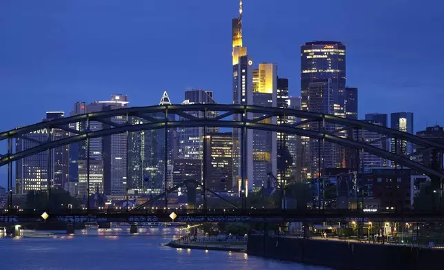 The lights of the buildings of the banking district are reflected in the river Main in Frankfurt, Germany, Wednesday, April 16, 2025. (AP Photo/Matthias Schrader)