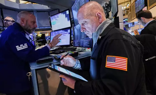 Specialist Meric Greenbaum, left and trader Michael Urkonis, center, work on the floor of the New York Stock Exchange, Wednesday, April 16, 2025. (AP Photo/Richard Drew)