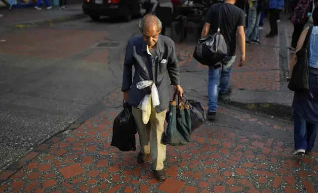 A coffee vendor crosses a street in Caracas, Venezuela, Thursday, April 10, 2025. (AP Photo/Ariana Cubillos)