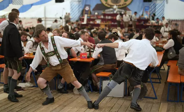 Competitors warm up for their bout while they try to pull the opponent over the table at the German Championships in Fingerhakeln or finger wrestling, in Pang, near Rosenheim, Germany, Sunday, April 27, 2025. (AP Photo/Matthias Schrader)