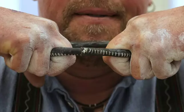 A competitor warms up for his bout while he try to pull the opponent over the table at the German Championships in Fingerhakeln or finger wrestling, in Pang, near Rosenheim, Germany, Sunday, April 27, 2025. (AP Photo/Matthias Schrader)
