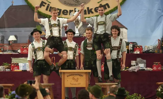 Competitors celebrates after their bouts while they try to pull the opponents over the table at the German Championships in Fingerhakeln or finger wrestling, in Pang, near Rosenheim, Germany, Sunday, April 27, 2025. (AP Photo/Matthias Schrader)
