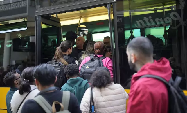 People try to board a crowded bus after the subway stopped running following a power outage in Lisbon, Portugal, Monday, April 28, 2025. (AP Photo/Armando Franca)