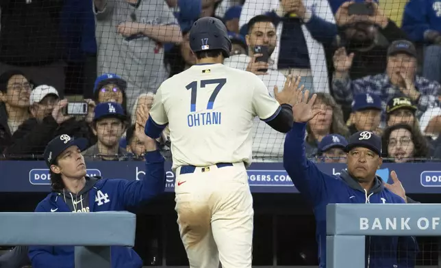 Los Angeles Dodgers' Shohei Ohtani, center, celebrates with bench coach Danny Lehmann, left, and Dave Roberts, right, after scoring on an RBI single by Freddie Freeman during the fifth inning of a baseball game against the Pittsburgh Pirates in Los Angeles, Saturday, April 26, 2025. (AP Photo/Kyusung Gong)