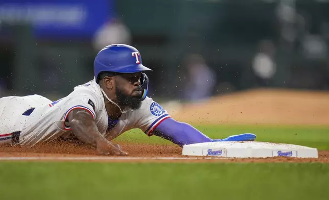 Texas Rangers' Adolis García steals third base against the Los Angeles Angels during the seventh inning of a baseball game Wednesday, April 16, 2025, in Arlington, Texas. (AP Photo/Julio Cortez)