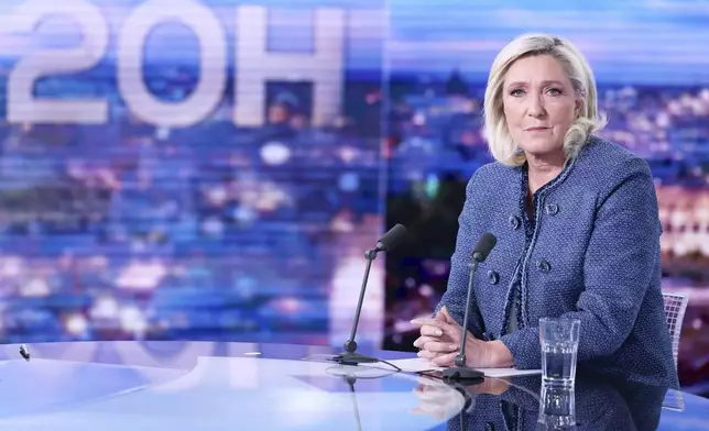 Far-right leader Marine Le Pen poses prior to an interview on the evening news broadcast of French TV channel TF1, after a French court convicted Marine Le Pen of embezzlement and barred her from seeking public office for five years, Monday, March 31, 2025, in Boulogne-Billancourt, outside Paris. (Thomas Samson, Pool via AP)