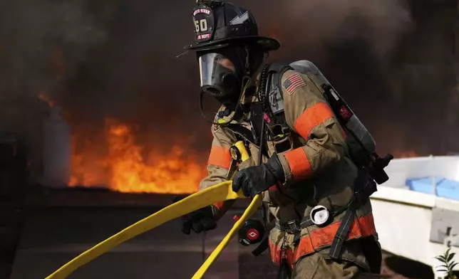 Firefighters battle a house fire Wednesday, April 23, 2025, in Lacey Township, N.J. (AP Photo/Matt Slocum)