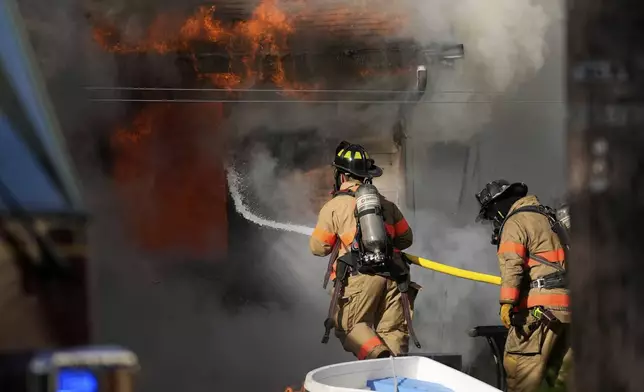Firefighters battle a house fire Wednesday, April 23, 2025, in Lacey Township, N.J. (AP Photo/Matt Slocum)