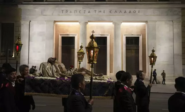 Men carrying the body of Jesus Christ pass the Bank of Greece headquarters during the Epitaph Procession of the Catholic Cathedral Basilica of St Dionysius the Areopagite in Athens, Greece, Good Friday, April 18, 2025. (AP Photo/Thanassis Stavrakis)