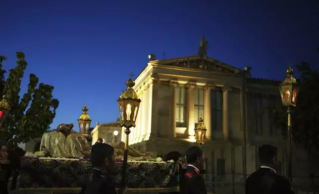 Men carrying a statue of Jesus Christ pass the Athens Academy during the Epitaph Procession of the Catholic Cathedral Basilica of St Dionysius the Areopagite in Athens, Greece, Good Friday, April 18, 2025. (AP Photo/Thanassis Stavrakis)