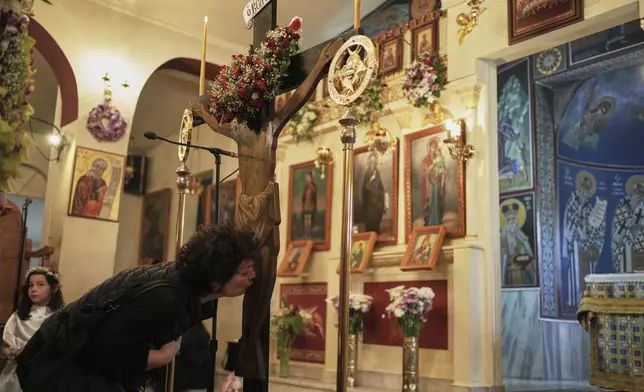 An Orthodox faithful kisses a crucifix during a Good Friday reenactment of Deposition of Jesus Christ, at Agios Antonios church in the northern suburb of Chalandri, in Athens, Greece, Friday, April 18, 2025. (AP Photo/Thanassis Stavrakis)