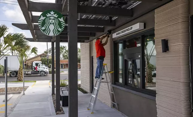 A construction worker adjusts a speaker at a 3D printed Starbucks building Monday, April 28, 2025, in Brownsville, Texas. (AP Photo/Michael Gonzalez)