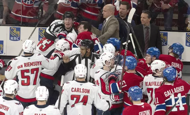 Montreal Canadiens' Josh Anderson (17) falls into the Washington Capitals' bench as he fights with Capitals' Tom Wilson (43) following the second period of Game 3 of a first-round NHL hockey playoff series in Montreal, Friday, April 25, 2025. (Christinne Muschi/The Canadian Press via AP)