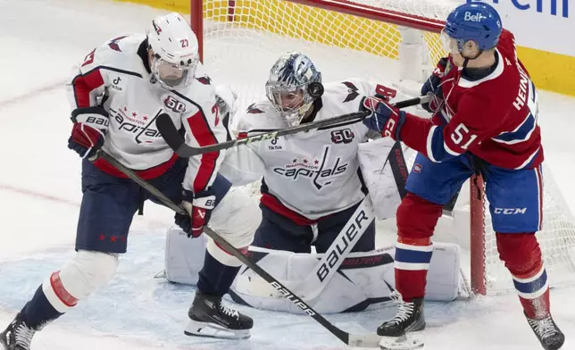 Montreal Canadiens' Emil Heineman (51) looks for a rebound in front of Washington Capitals goaltender Logan Thompson, center, and Alexander Alexeyev (27) during the second period of Game 3 of a first-round NHL hockey playoff series in Montreal, Friday, April 25, 2025. (Christinne Muschi/The Canadian Press via AP)