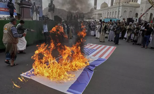 Houthi supporters burn an American and and an Israeli flags during a rally in Sanaa, Yemen, Friday, April 18, 2025. (AP Photo/Osamah Abdulrahman)