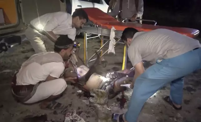 This photo taken from video released by Al Masirah TV channel shows medics carrying a severely wounded person onto a stretcher after U.S. airstrikes targeted the Ras Isa oil port held by Yemen's Houthi rebels in Hodeida, Yemen, Friday, April 18, 2025.( Al Masirah TV via AP)