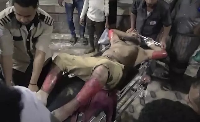This photo taken from video released by Al Masirah TV channel shows medics carrying a wounded man into the hospital after U.S. airstrikes targeted the Ras Isa oil port held by Yemen's Houthi rebels in Hodeida, Yemen, Friday, April 18, 2025.( Al Masirah TV via AP)