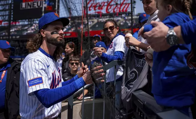 New York Mets outfielder Jesse Winker (3) signs baseballs for fans before a baseball game against the St. Louis Cardinals, Sunday, April 20, 2025, in New York. (AP Photo/Angelina Katsanis)