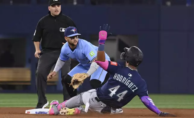 Seattle Mariners' Julio Rodriguez (44) slides safely into second base ahead of a tag by Toronto Blue Jays shortstop Bo Bichette (11) after a throwing error on a dropped third strike in the fourth inning of a baseball game in Toronto on Sunday, April 20, 2025. (Jon Blacker/The Canadian Press via AP)