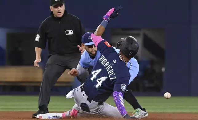 Seattle Mariners' Julio Rodriguez (44) slides safely into second base ahead of a tag by Toronto Blue Jays shortstop Bo Bichette (11) after a throwing error on a dropped third strike in the fourth inning of a baseball game in Toronto on Sunday, April 20, 2025. (Jon Blacker/The Canadian Press via AP)