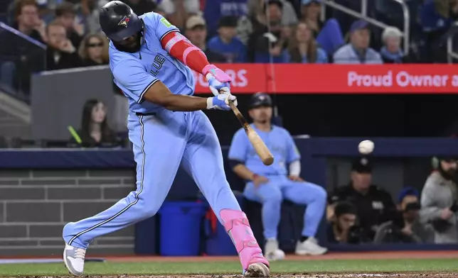 Toronto Blue Jays' Vladimir Guerrero Jr (27) hits a single to load the bases against the Seattle Mariners in the second inning of a baseball game in Toronto on Sunday, April 20, 2025. (Jon Blacker/The Canadian Press via AP)