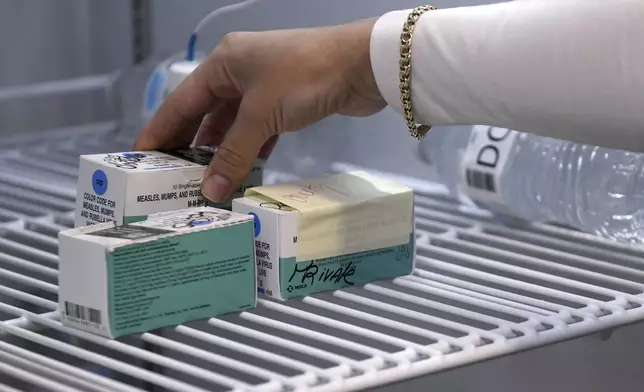 Anna Hicks places the measles, mumps and rubella vaccine in a refrigerator at the Andrews County Health Department's measles clinic, Tuesday, April 8, 2025, in Andrews, Texas. (AP Photo/Annie Rice)