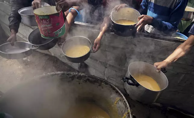 Palestinian children wait to receive donated food at a distribution center in Muwasi, on the outskirts of Khan Younis in the southern Gaza Strip, Thursday, April 24, 2025. (AP Photo/Abdel Kareem Hana)