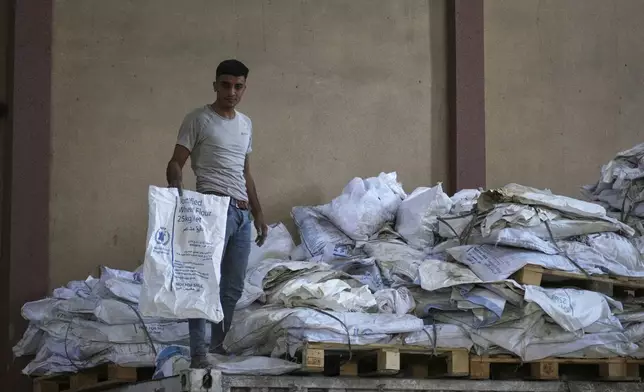 A Palestinian worker holds one of the empty sacks of flour at the World Food Program warehouse in the Nuseirat refugee camp, Gaza Strip, Saturday April 26, 2025. (AP Photo/Abdel Kareem Hana)
