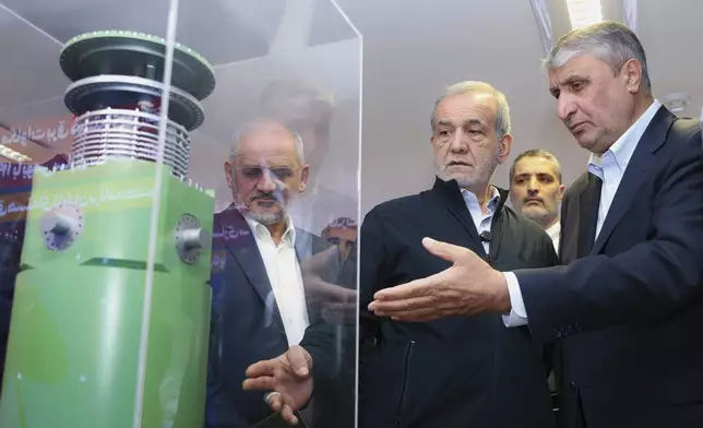 In this photo released by the Iranian Presidency Office, President Masoud Pezeshkian, second right, listens to head of Atomic Energy Organization of Iran Mohammad Eslami as he visits an exhibition of Iran's nuclear achievements, in Tehran, Iran, Wednesday, April 9, 2025. (Iranian Presidency Office via AP)