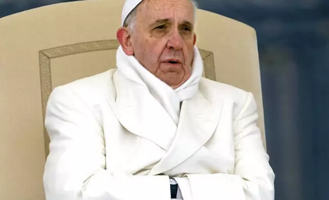 FILE - Pope Francis tries to keep himself warm as he attends his weekly general audience in St. Peter's Square at the Vatican, Wednesday, Nov. 27, 2013. (AP Photo/Alessandra Tarantino, File )