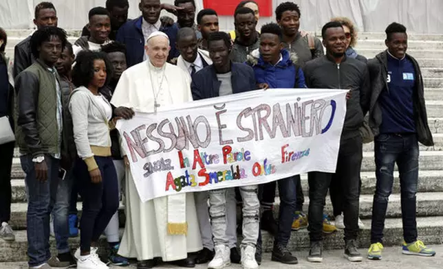 FILE - Pope Francis meets a group of migrants taking part in a project on social integration organized by the charity "Agata Smeralda", during his weekly general audience, in St.Peter's Square at the Vatican, Wednesday, April 11, 2018. Writing on the banner reads in Italian "No one is foreign". (AP Photo/Andrew Medichini, file)