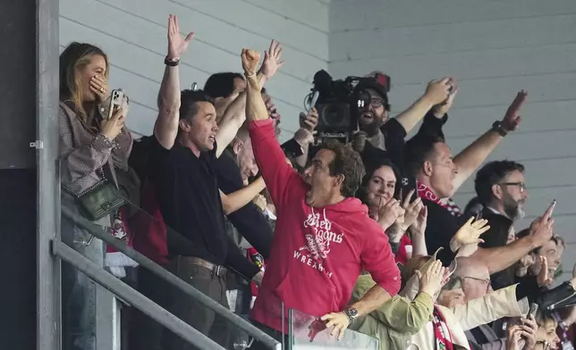 Wrexham co-owners Ryan Reynolds, center, and Rob McElhenney celebrate at the end of the English League One soccer match between Wrexham and Charlton Athletic at the Racecourse ground in Wrexham, Wales, Saturday, April 26, 2025. (AP Photo/Jon Super)