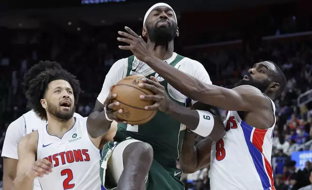 Milwaukee Bucks forward Bobby Portis (9) tries going to the basket between Detroit Pistons guard Cade Cunningham (2) and forward Tim Hardaway Jr. (8) during the first half of an NBA basketball game Friday, April 11, 2025, in Detroit. (AP Photo/Duane Burleson)