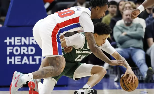 Detroit Pistons forward Ronald Holland II (00) and Milwaukee Bucks guard Ryan Rollins (13) scramble for a loose ball during the first half of an NBA basketball game Friday, April 11, 2025, in Detroit. (AP Photo/Duane Burleson)