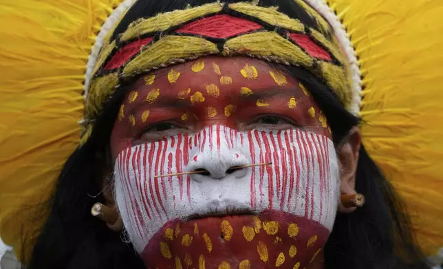An Indigenous woman attends in the annual Free Earth camp where Brazil's Indigenous communities discuss rights, territorial protection and their role in COP30 which will take place for the first time in the Amazon, in Brasilia, Brazil, Tuesday, April 8, 2025. (AP Photo/Eraldo Peres)